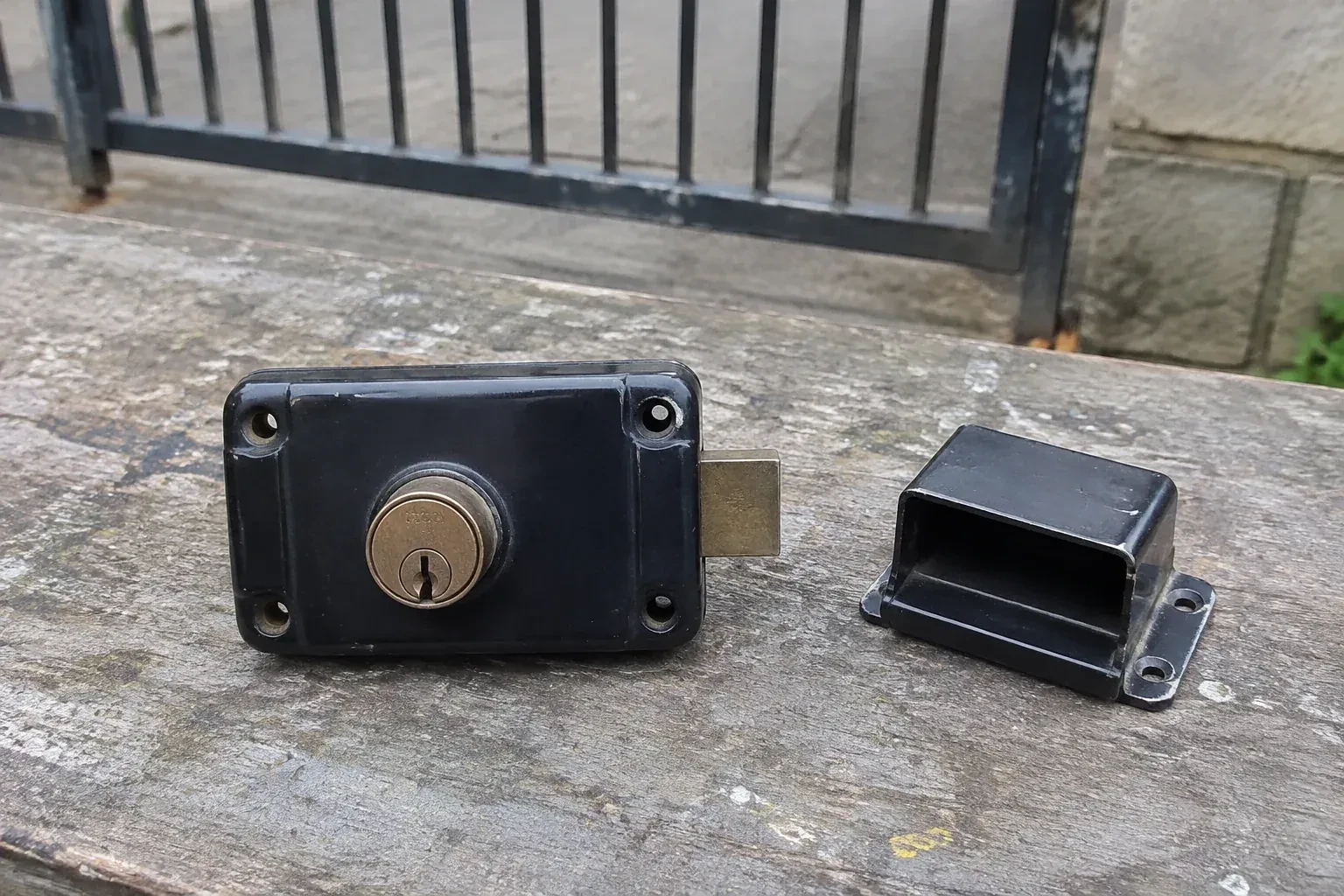 Detached rim gate lock and separate box keeper on an outdoor workbench. — Gate & Building Entry Locks, Brampton
